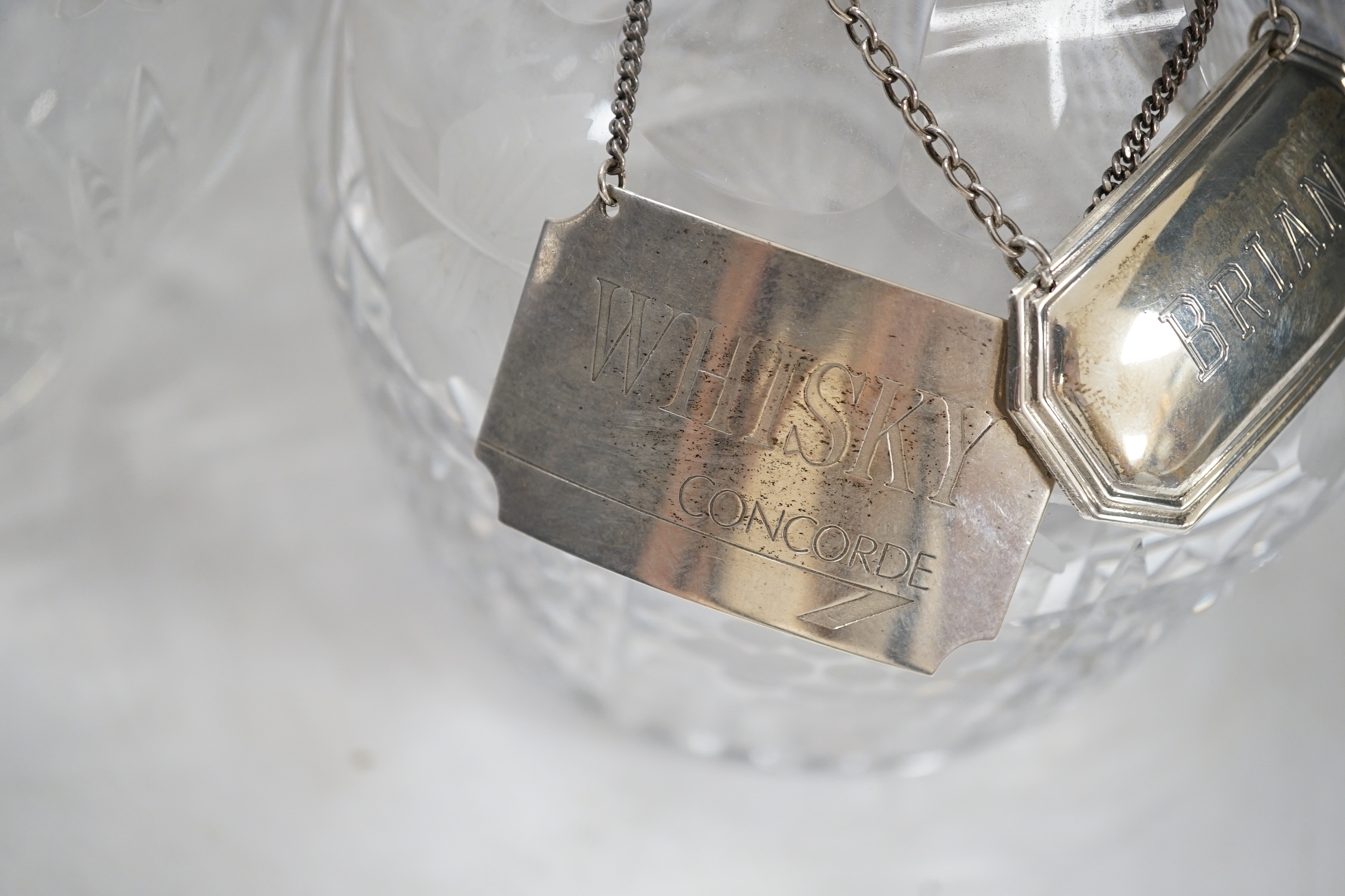 A silver mounted cut glass decanter with silver Concorde label and another label, together with a cut glass urn and a moulded glass basket, urn 28.5cm